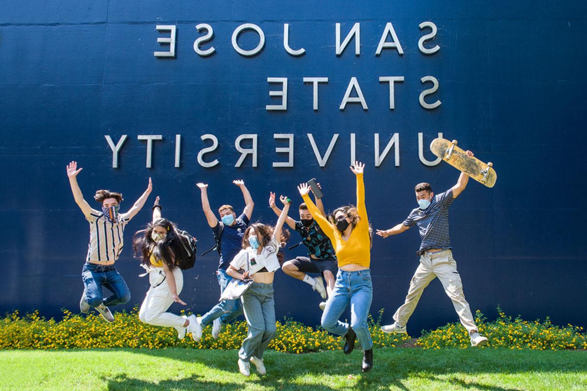 Students jumping in front of a wall that says San Jose State University.